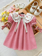 Vestido Kabannas xadrez vermelho e branco com gola bordada de patos, mangas bufantes e laço frontal para bebês.